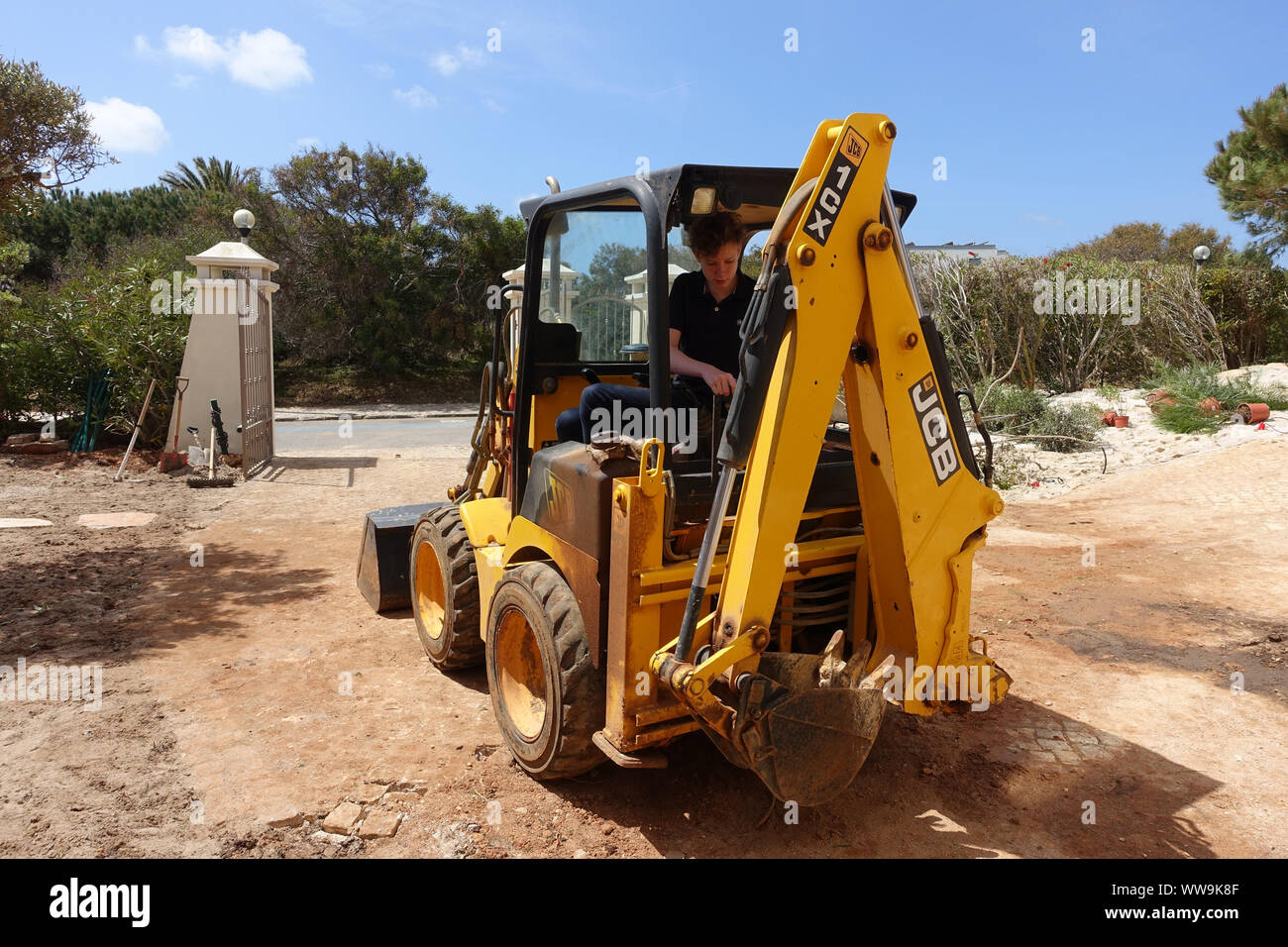 Algarve, Portugal 10 April 2019: A JCB mini digger being used to do landscaping work in a front garden Stock Photo