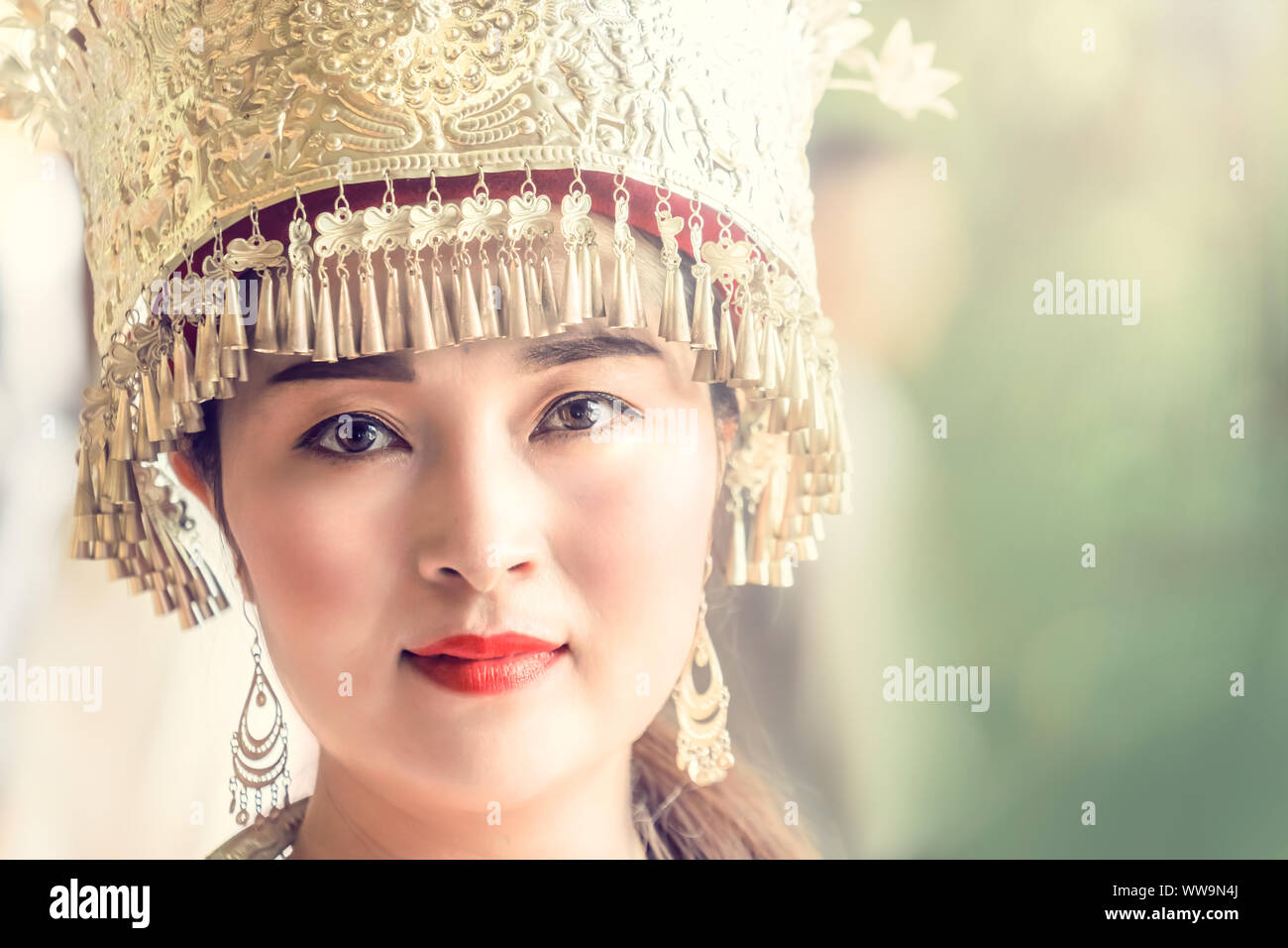 Zhangjiajie, China -  August 2019 : Cultural portrait of a beautiful chinese woman in a traditional chinese dress, wearing a golden decorated hat and Stock Photo