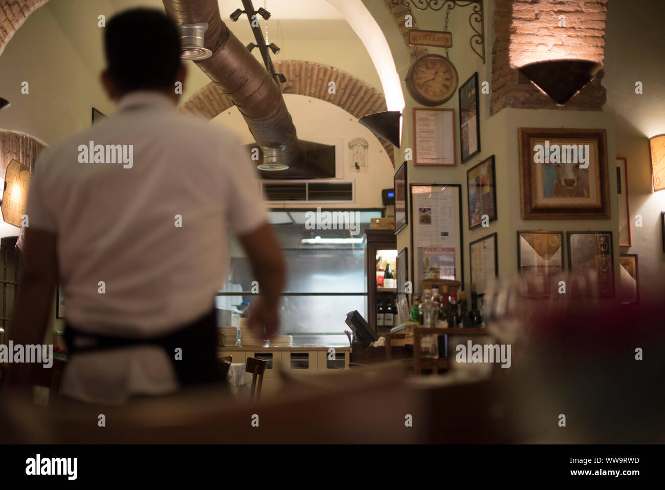 Rome, Italy - July 5, 2018: A waiter in a white shirt and apron moves quickly through a restaurant in Rome. Stock Photo