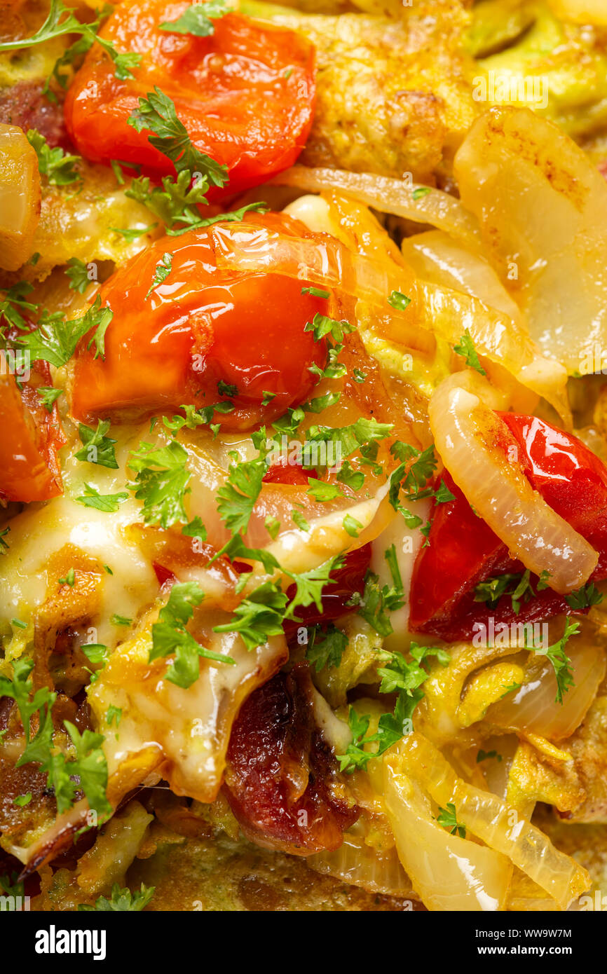Fresh omelette with onion, pork sausages, tomatoes and cheese - close up view Stock Photo