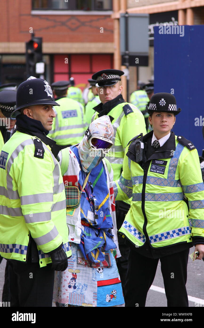 POLITICAL PROTESTOR DETAINED IN THE CITY OF LONDON. ANTI CAPITALIST PROTESTOR HIDING FACE. FACE COVERING. HIDING IDENTITY ON STREETS OF THE UNITED KINGDOM. ANTI CAPITALIST DEMONSTRATION. Stock Photo