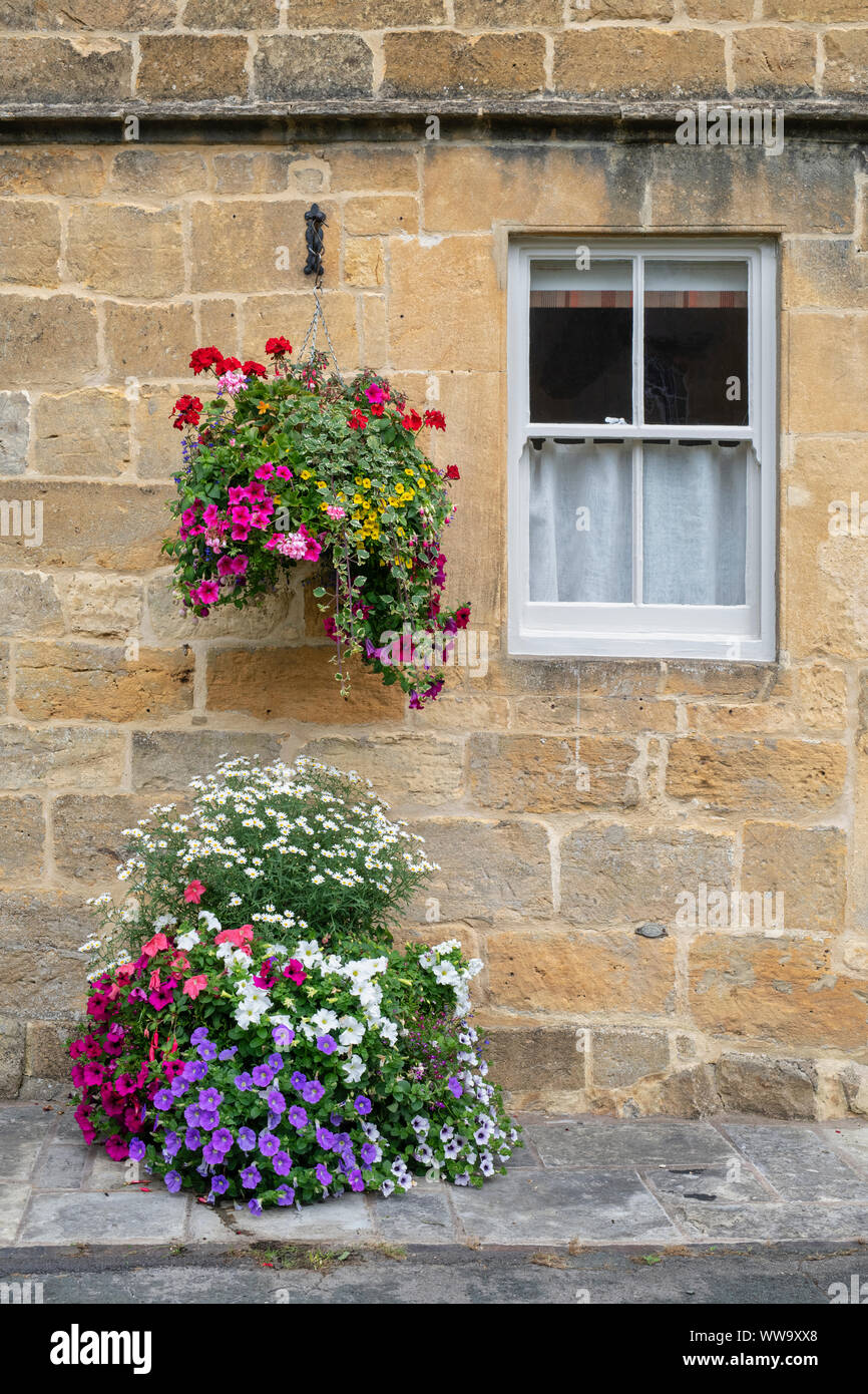 Floral hanging basket and planter outside Milestone house in the cotswold village of Broadway, Worcestershire, England Stock Photo