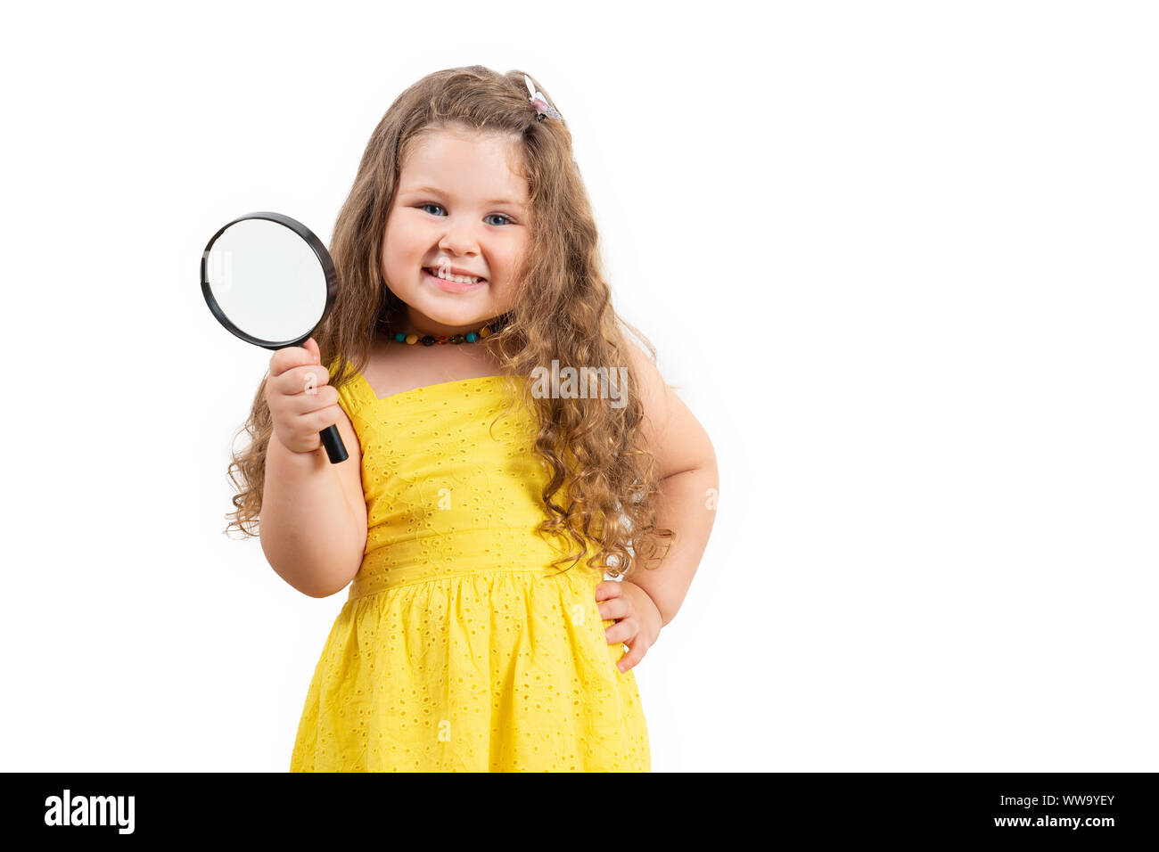 Little preschool girl holding magnifier and smiling on white background. Stock Photo
