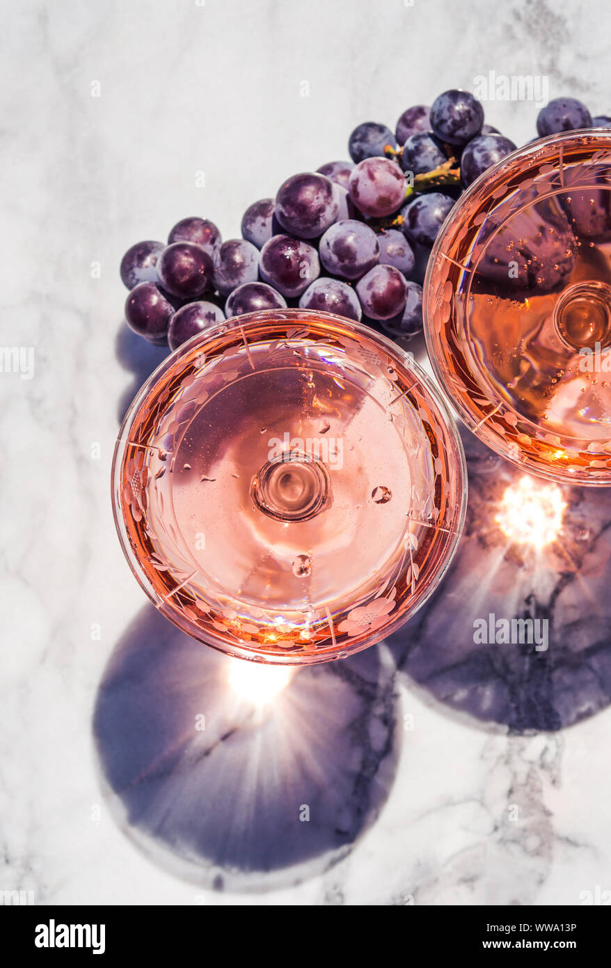 Two crystal stemmed glasses with rose wine on marble table outdoors in a cafe. Aperitif and relax time Stock Photo