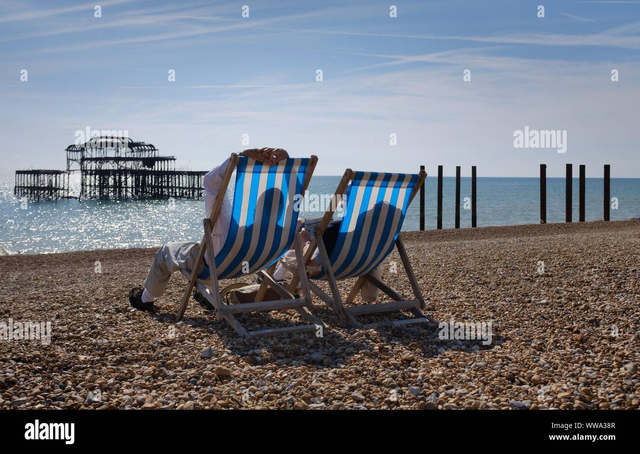 Relaxing on the deckchairs on Brighton beach Stock Photo