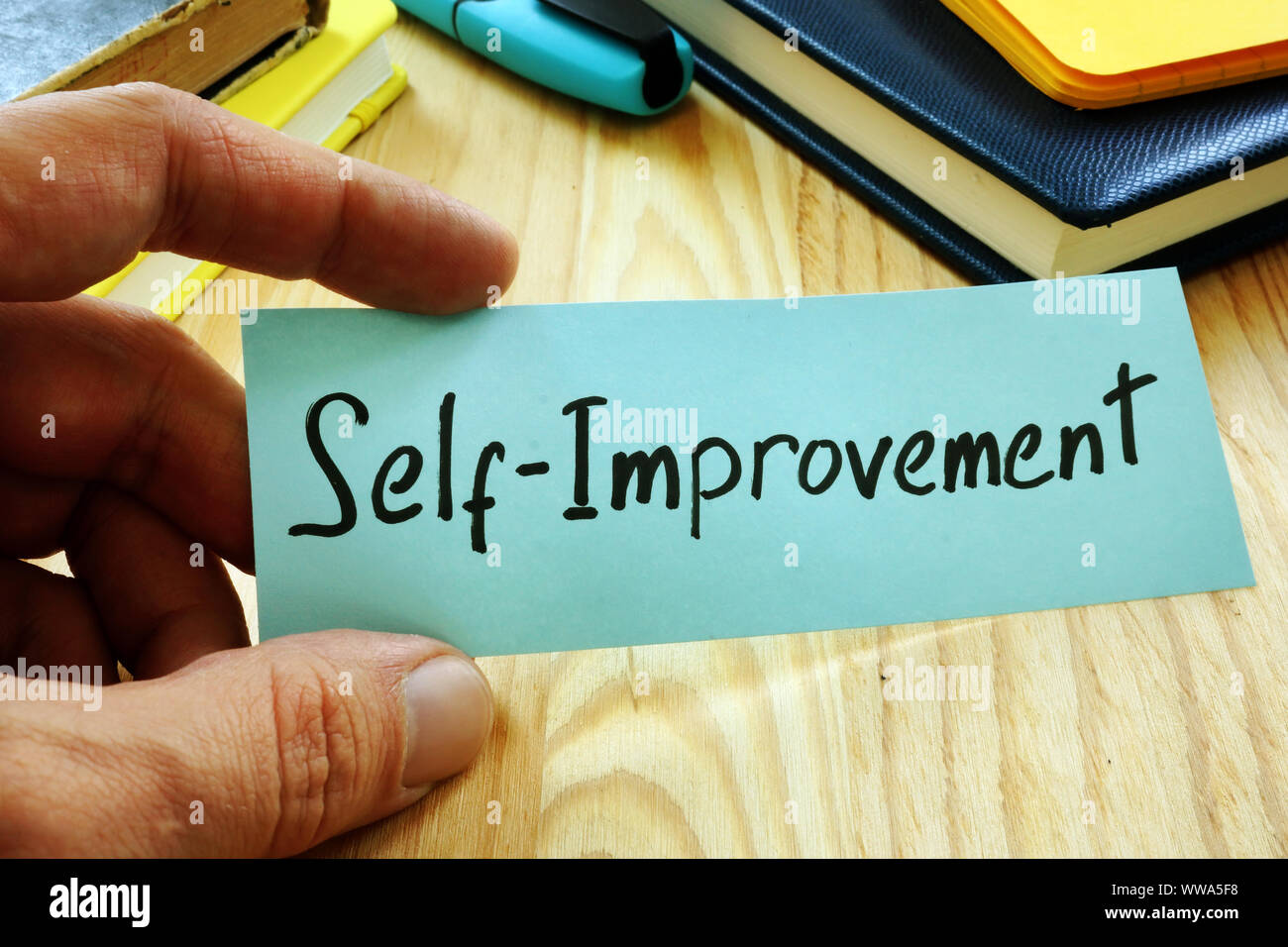 Hand holds piece of paper with sign Self improvement. Stock Photo