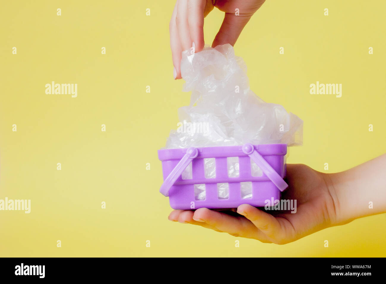 polythene bags in hand in shopping basket on yellow background Stock Photo