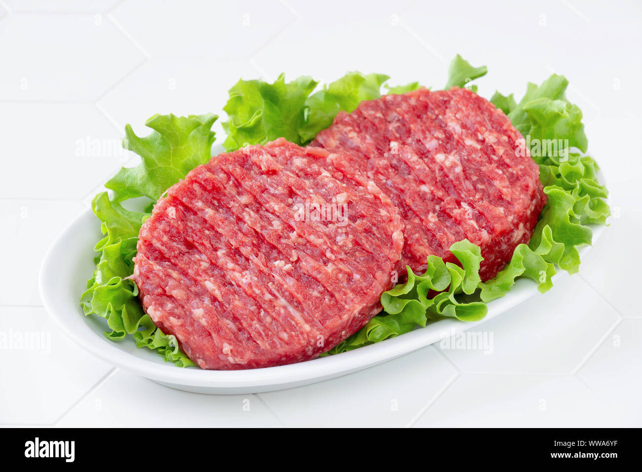 Raw mince meat beef burgers on a white plate Stock Photo