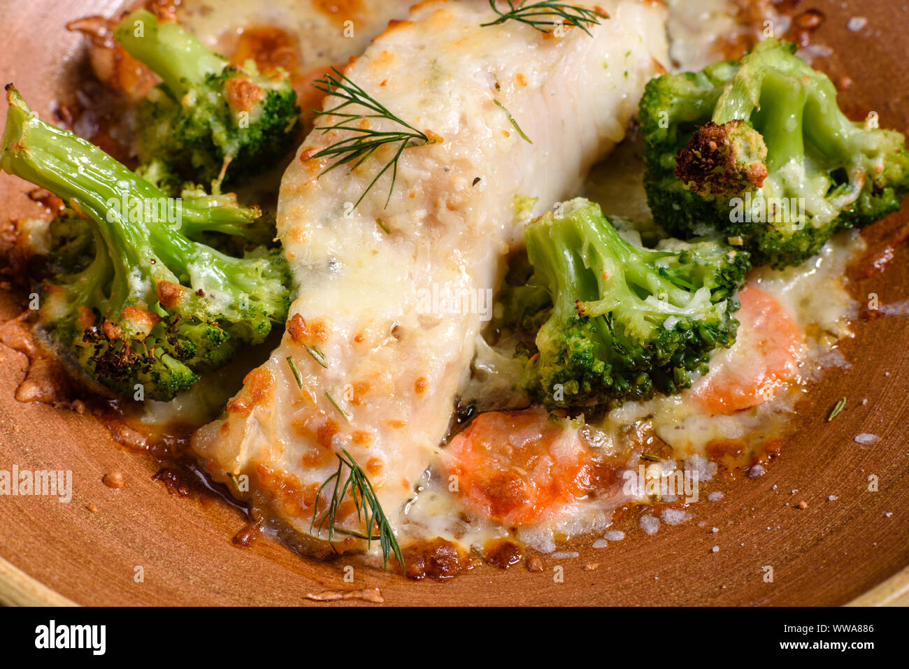 Fresh baked sea fish with broccoli, carrots, vegetables and cheese
