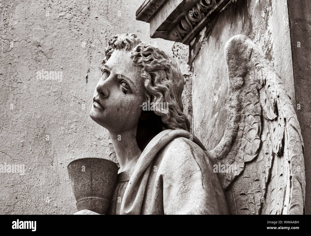 Weathered stone statue of angel in cemetery. Stock Photo