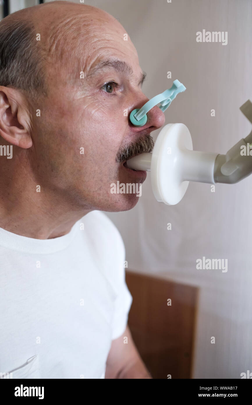 Senior hispanic man man testing breathing function by spirometry ...