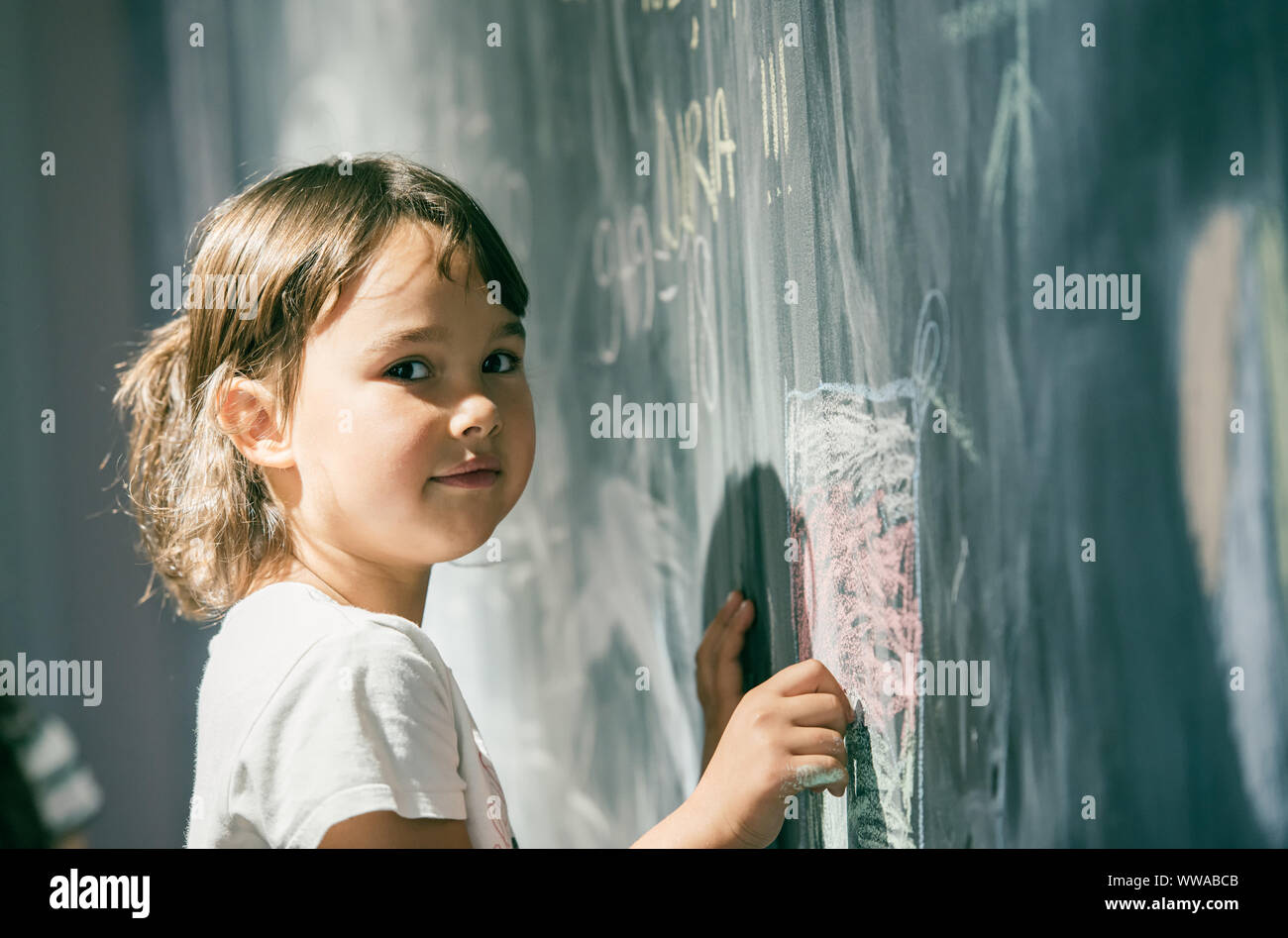 Beautiful little girl drawing on a blackboard at playground Stock Photo