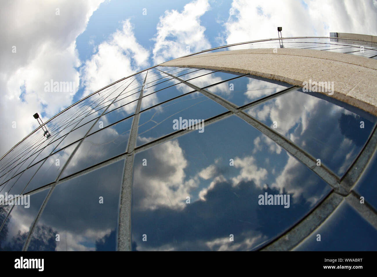 A blue sky with white clouds reflecting from a tile wall of a modern ...