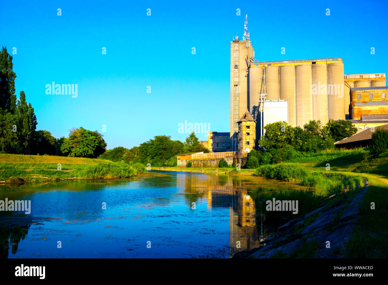 View on big and old concrete grain silos in urban landscape by the lake. Stock Photo