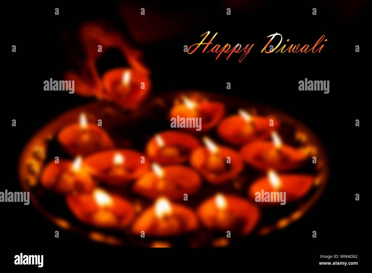 Background image for Happy Diwali - an Indian festival of lights. An abstract blur picture of diya oil lamp with copy space and Happy Diwali written o Stock Photo