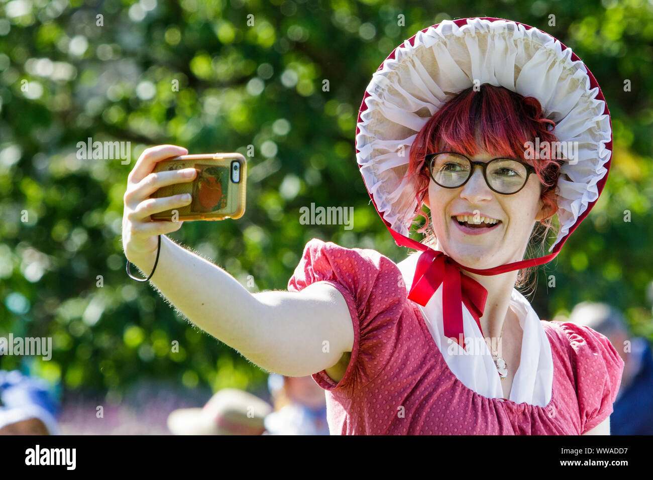 Bath, Somerset, UK. 14 Sep, 2019. A Jane Austen fan is pictured taking a selfie as she takes part in the world famous Grand Regency Costumed Promenade. The Promenade, part of the Jane Austen Festival is a procession through the streets of Bath and the participants who come from all over the world dress in 18th Century costume. Credit:  Lynchpics/Alamy Live News Stock Photo