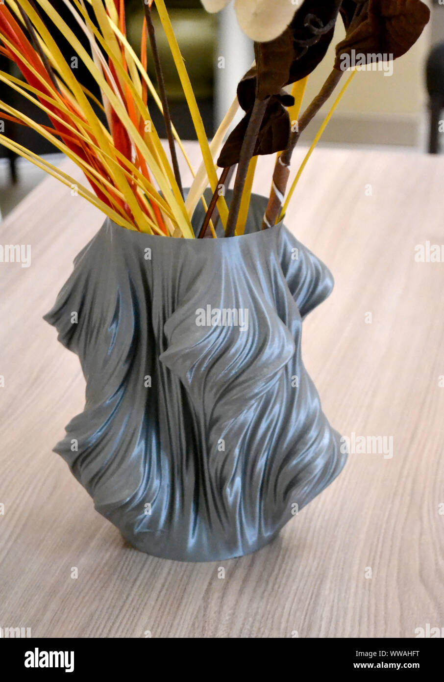 A gray vase printed on a 3d printer stands on a table in the interior ...