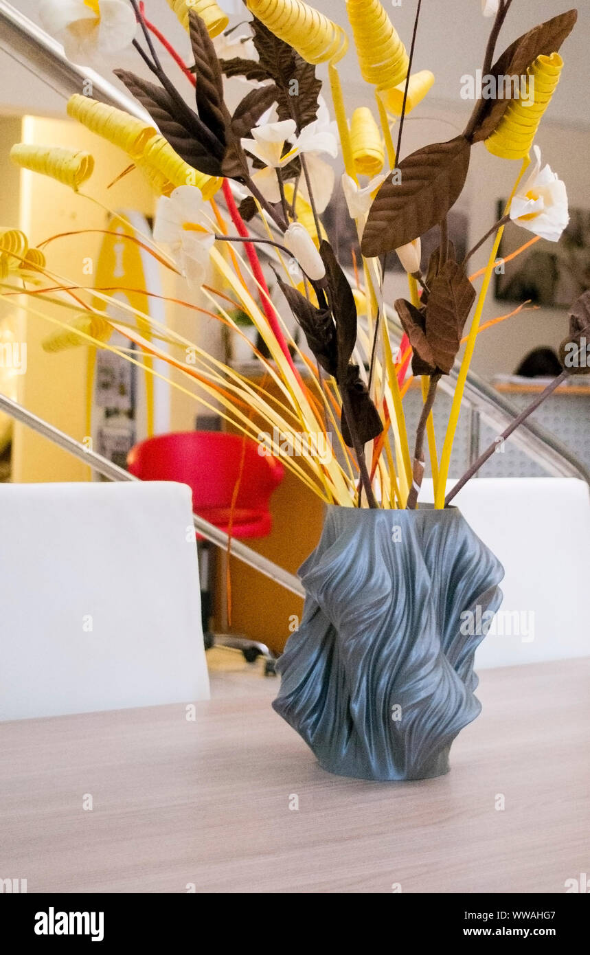 A gray vase printed on a 3d printer stands on a table in the interior ...