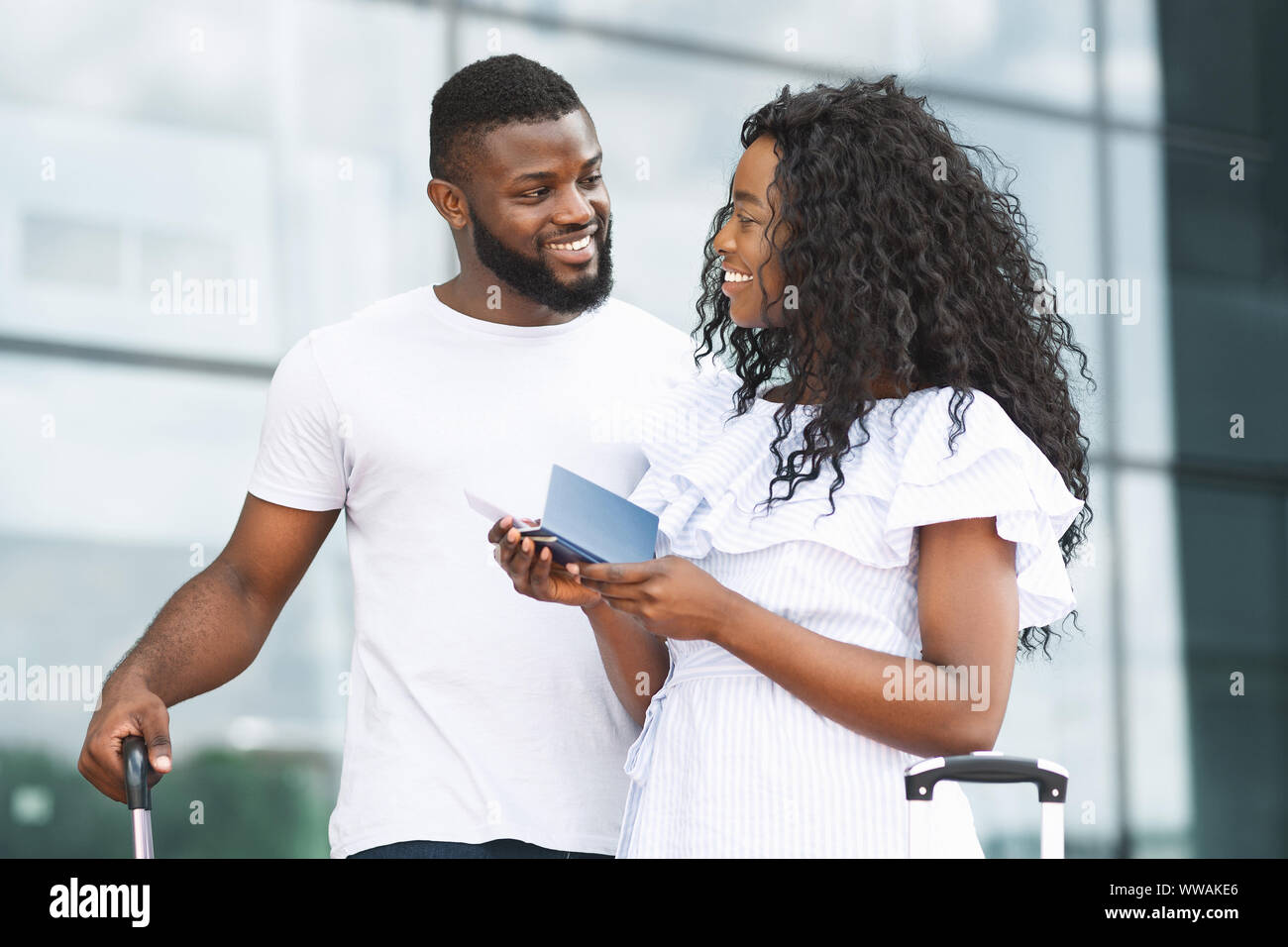 Happy african couple standing at airport building Stock Photo - Alamy