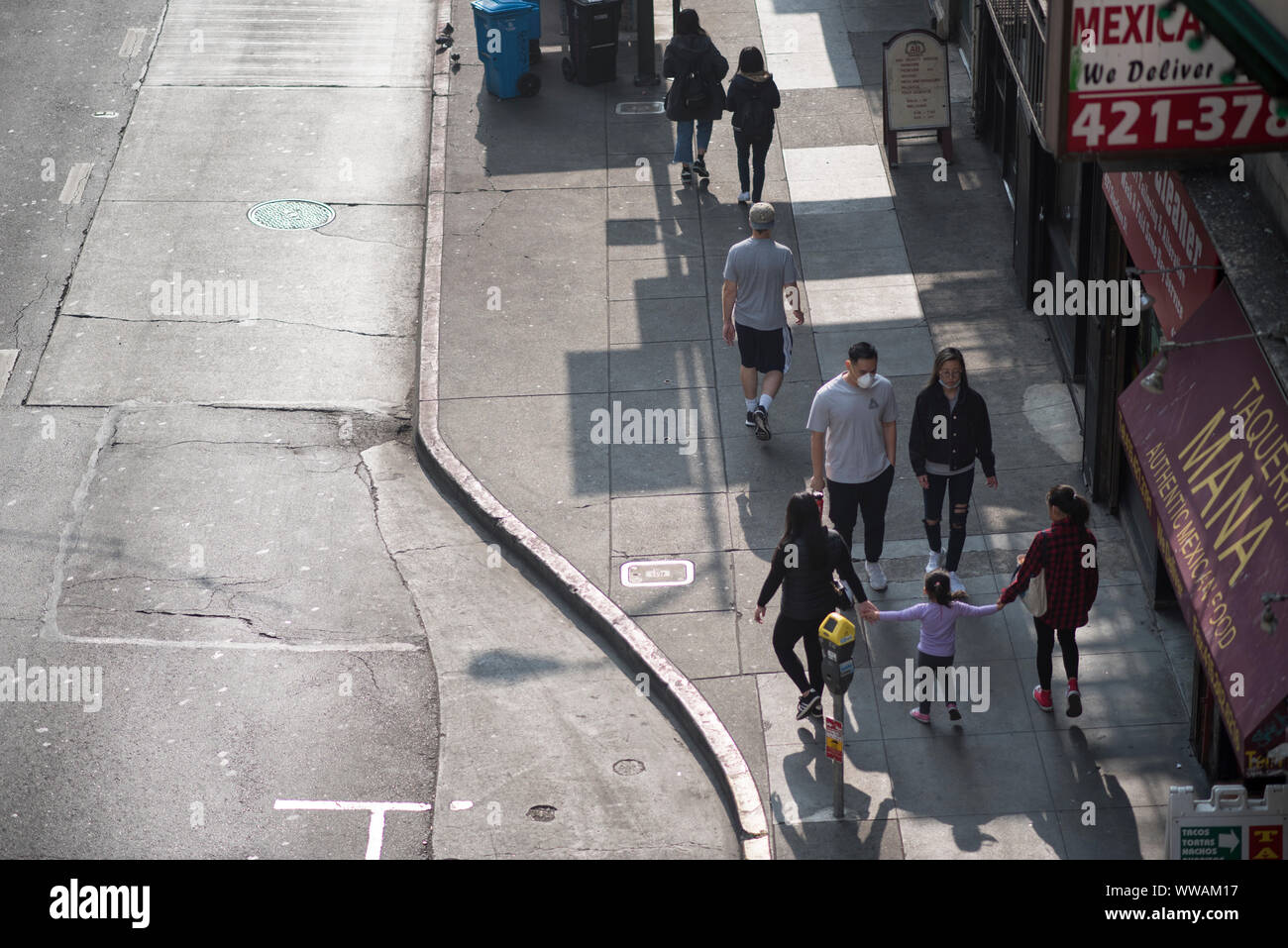 San Francisco, California - November 17, 2018: People walking on the sidewalk have air filter masks for the smoke from the Camp Fire. Stock Photo