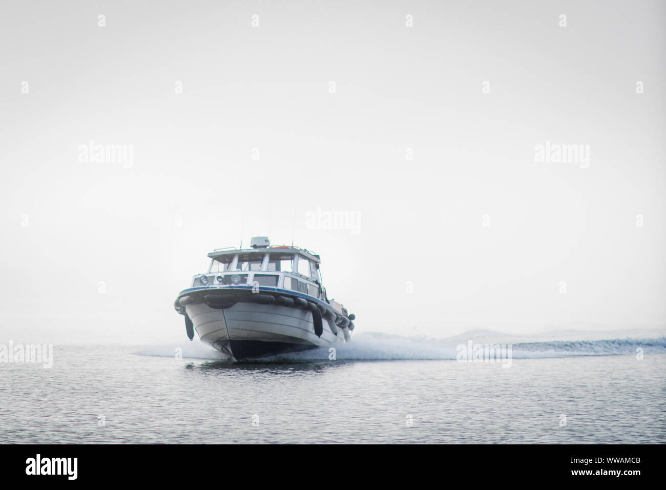 A taxi boat shoots through the fog as it arrives the Kirkebukta landing on Skåtøy outside Kragerø in Norway. Stock Photo