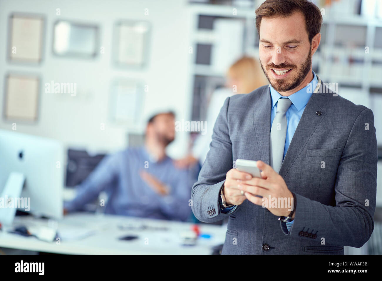 Smiling business man using mobile phone in office Stock Photo