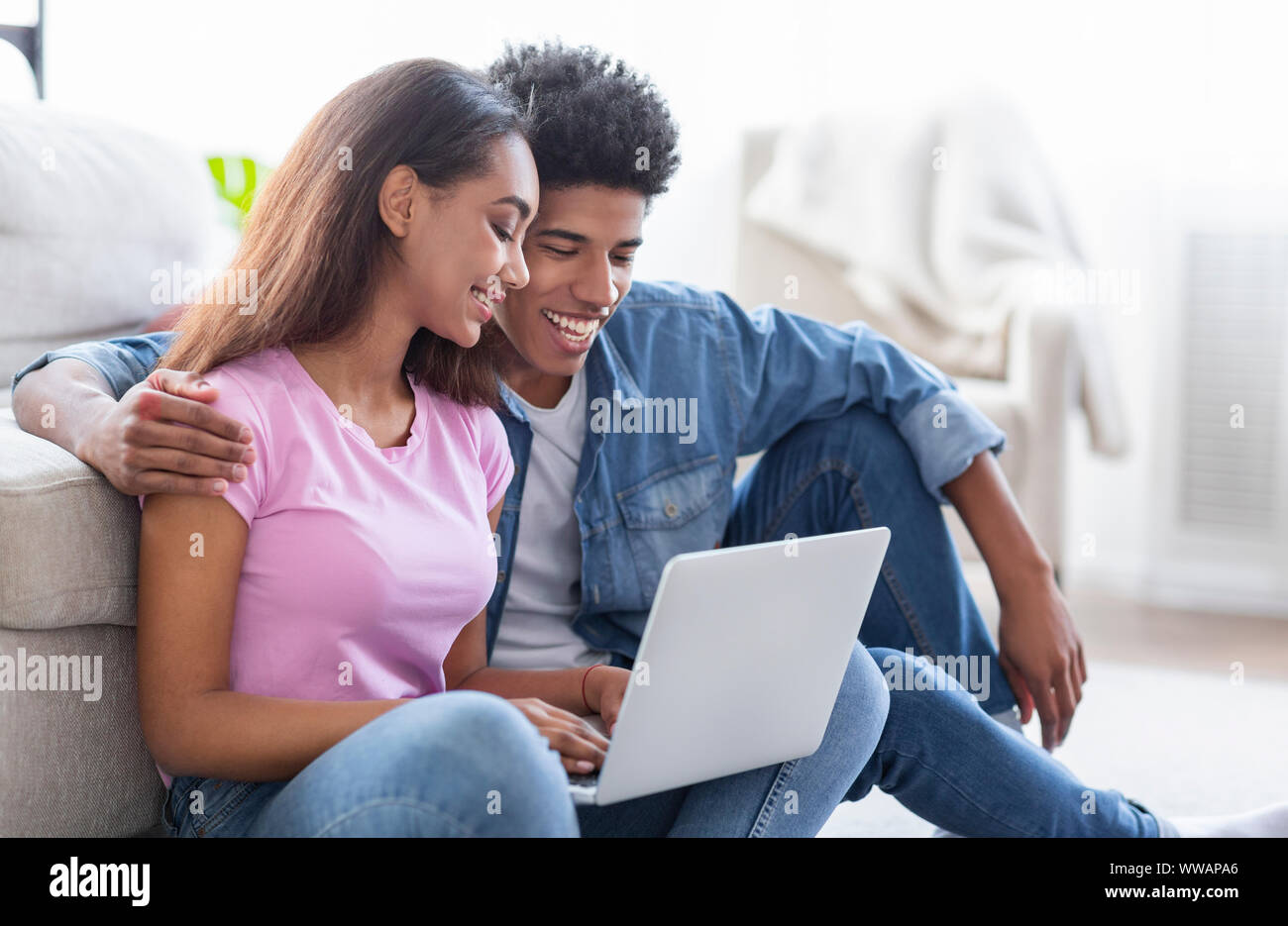African American couple using laptop together sitting on floor Stock ...