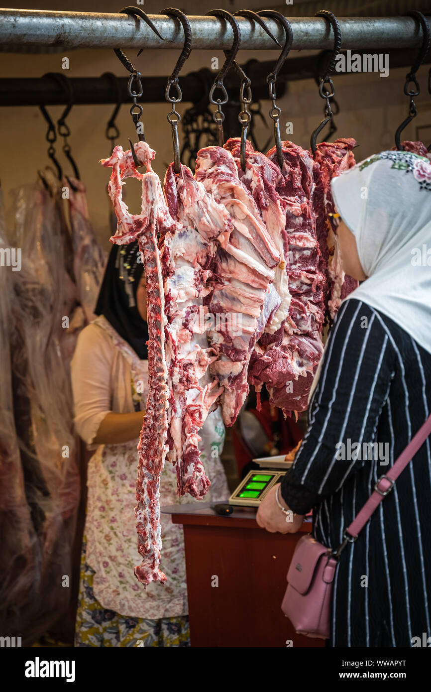 Xian, China -  July 2019 : Muslim woman buying lamb and cow carcass meat from the street food vendors shop in the Muslim quarter of Xian town, Shaanxi Stock Photo