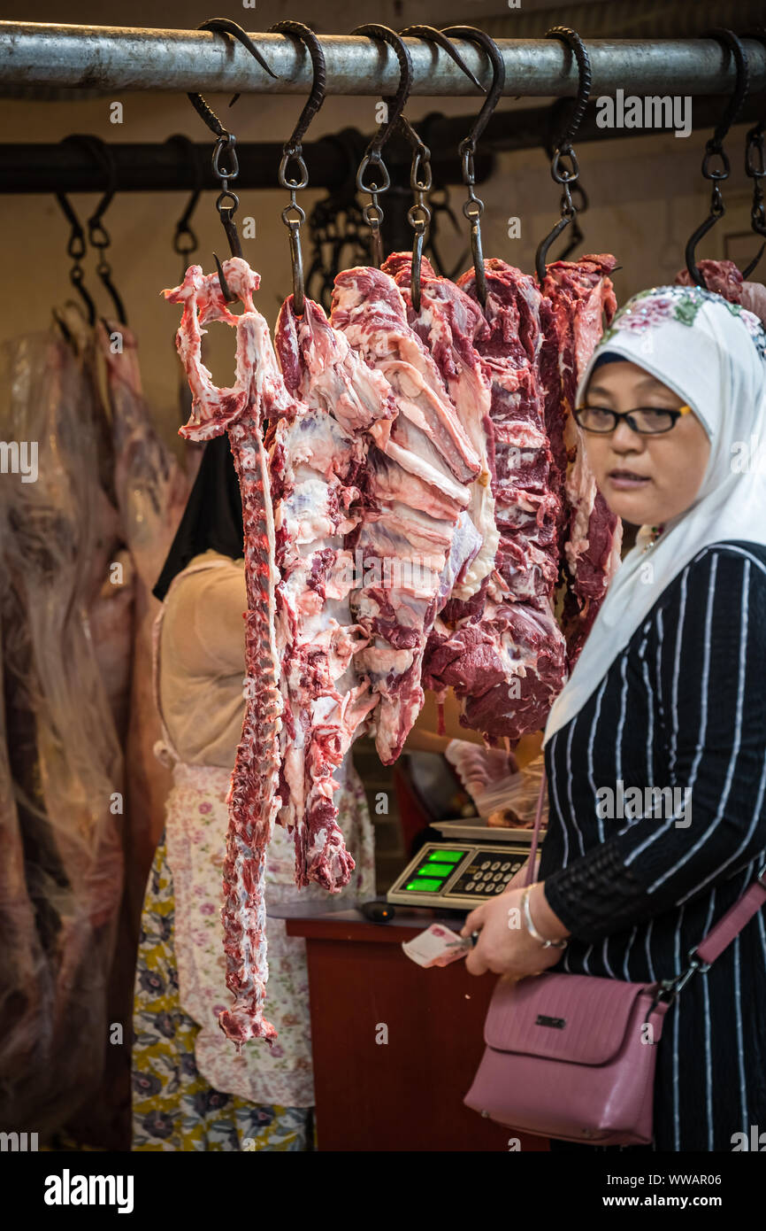 Xian, China -  July 2019 : Muslim woman buying lamb and cow carcass meat from the street food vendors shop in the Muslim quarter of Xian town, Shaanxi Stock Photo