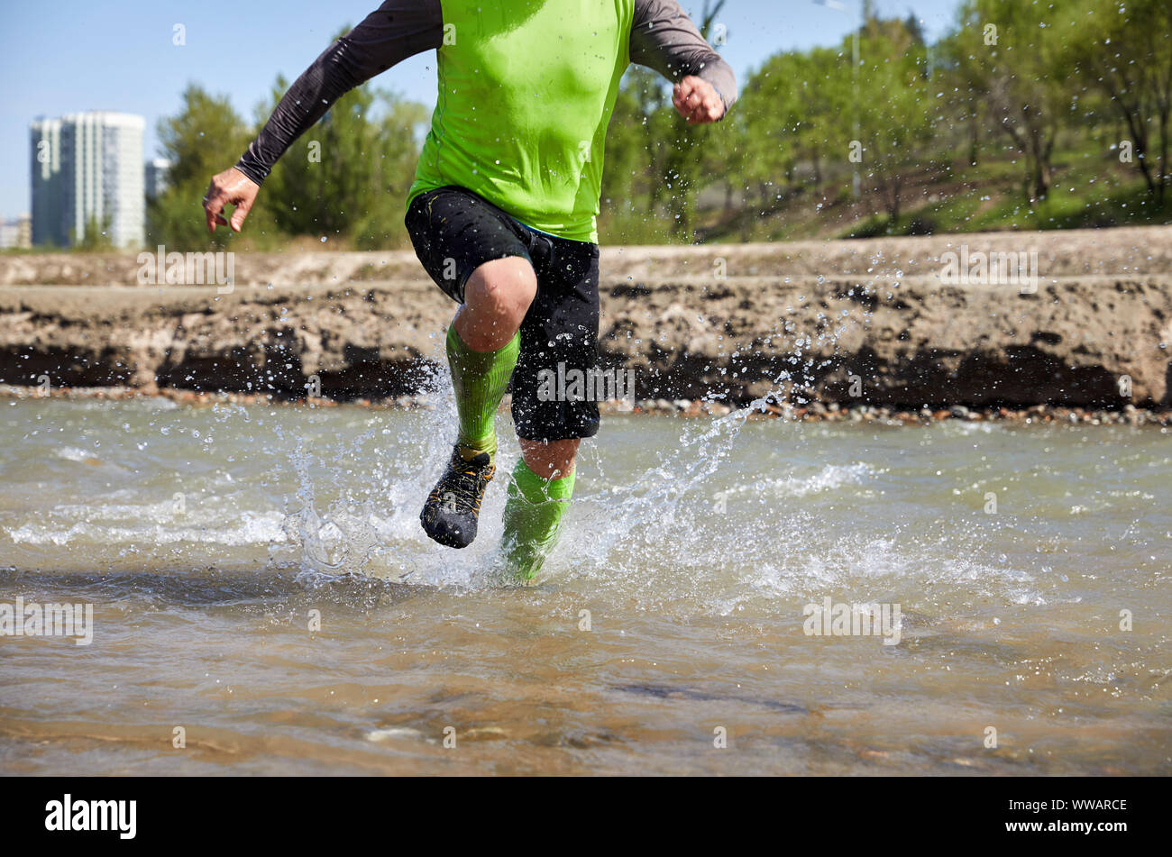 Legs of runner close up the river with splashes Stock Photo