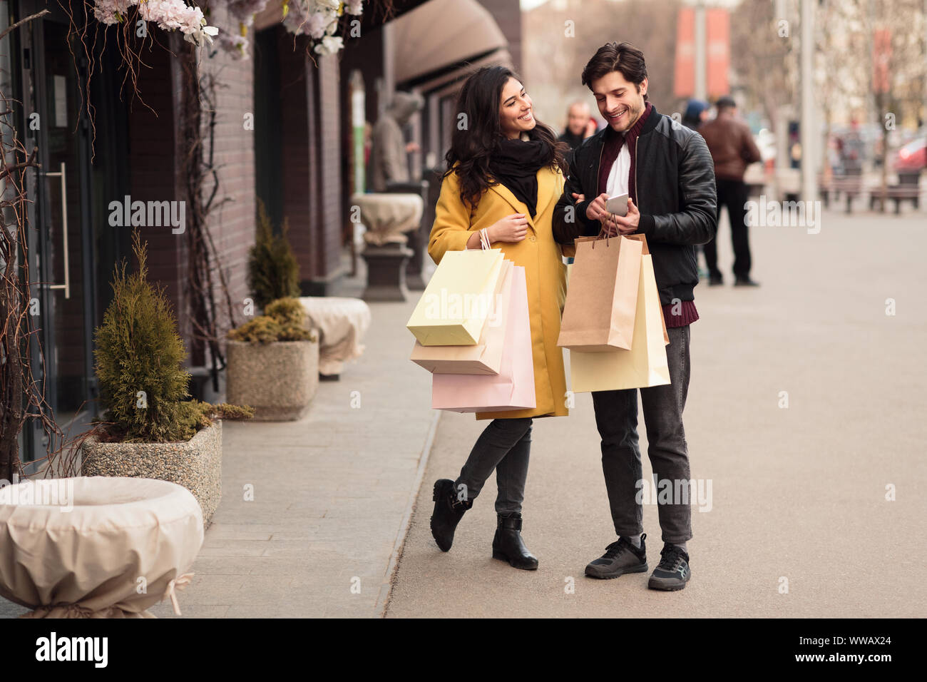 Consumerism concept. Young couple using smartphone outdoors Stock Photo