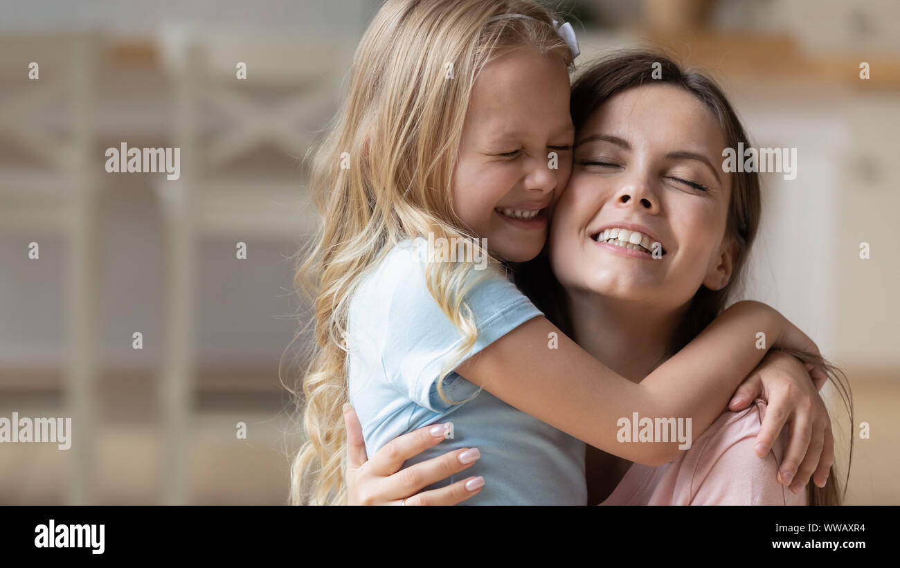 Adorable blonde adopted little girl cuddling mommy. Stock Photo
