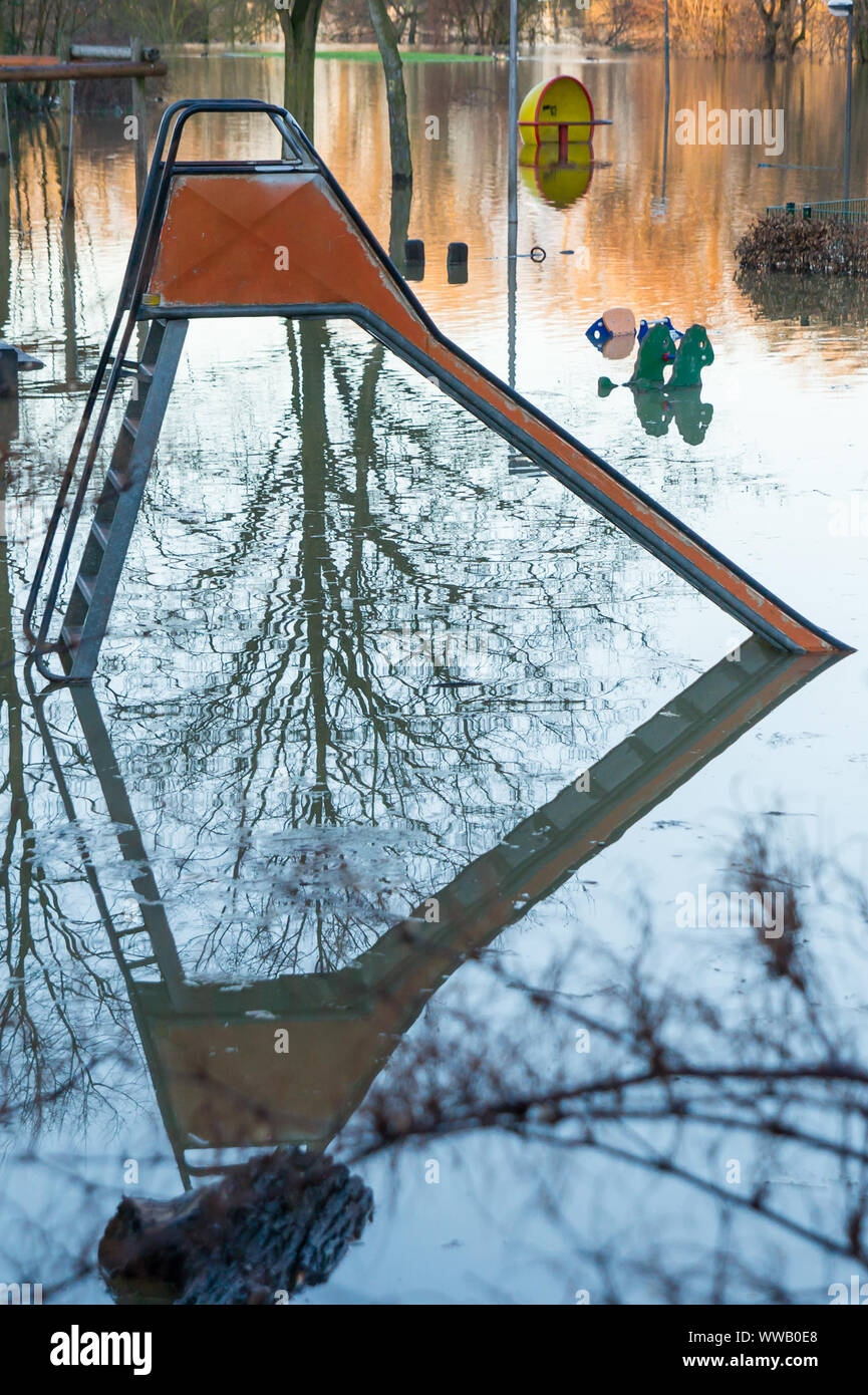 Slide on a flooded playground with reflection in the water. Scene from the Rhine shore. Stock Photo
