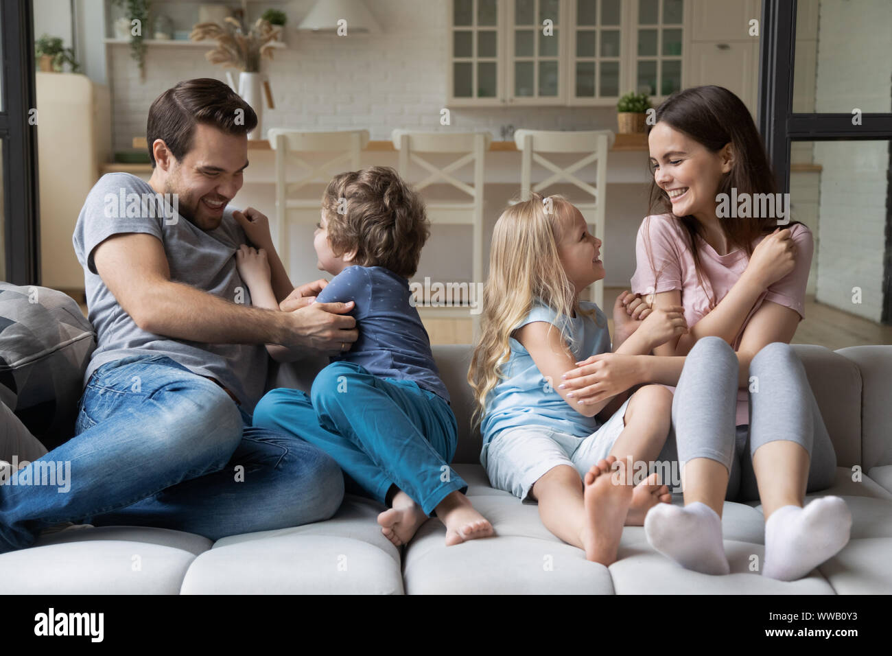Joyful family of four enjoying fun time on comfortable couch Stock ...