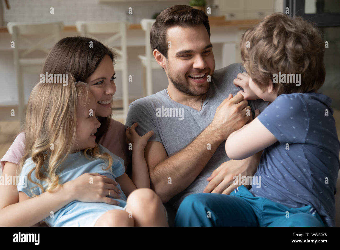 Overjoyed parents enjoying leisure weekend time with small kids. Stock Photo