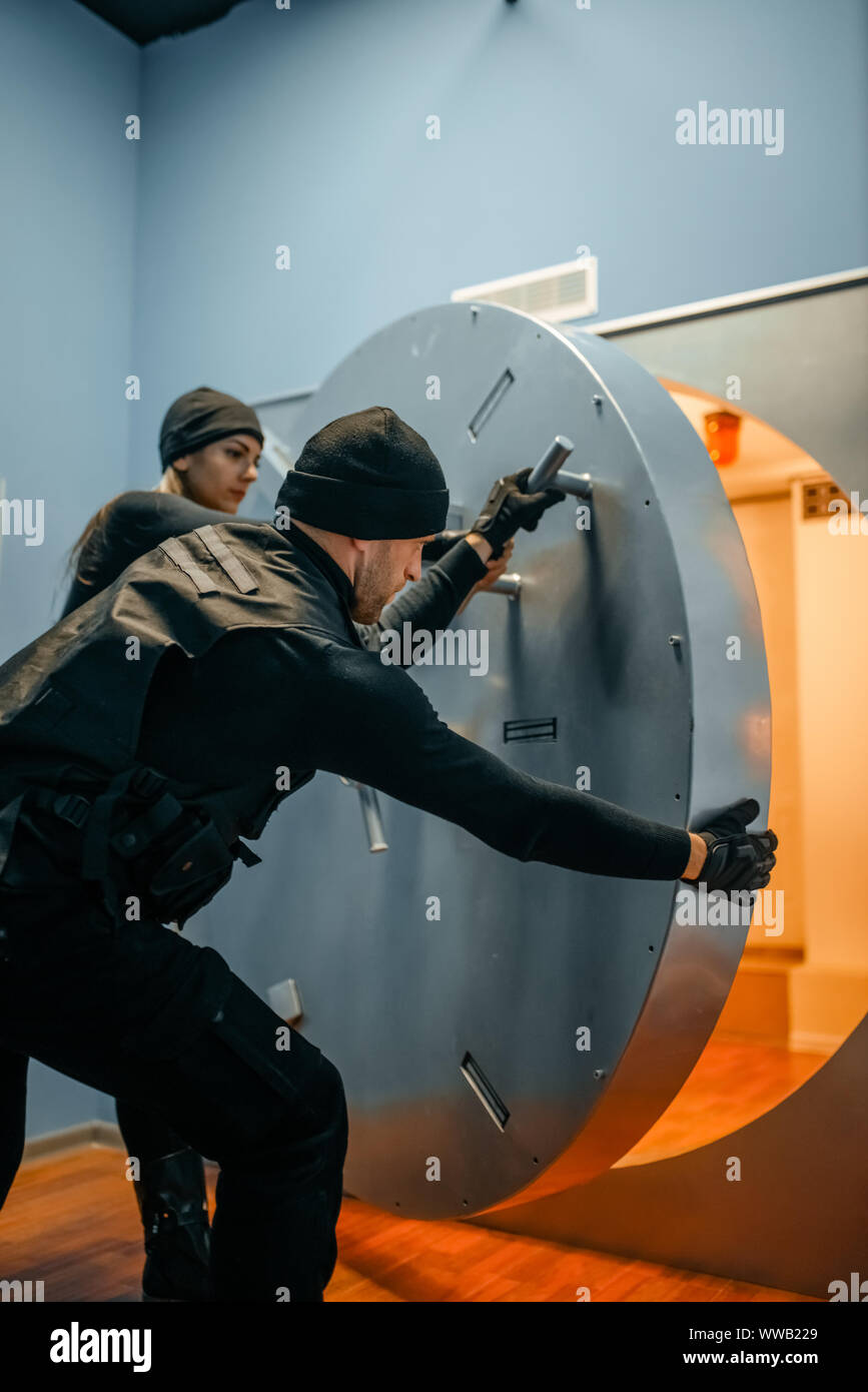 Robbers in black uniform opening vault door Stock Photo