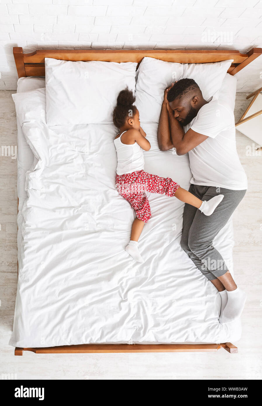 Little african girl sleeping with daddy on big parent bed Stock Photo -  Alamy