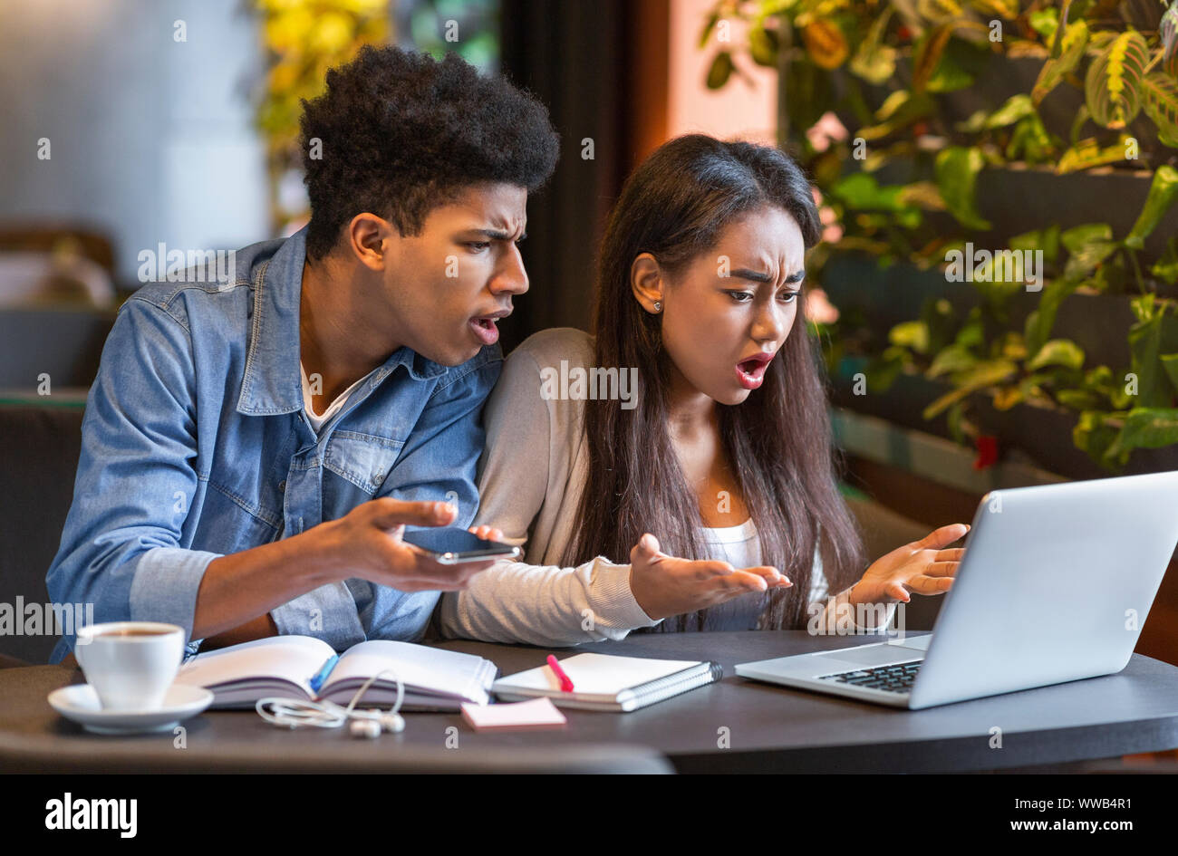 Desperate students looking at laptop with furious faces Stock Photo