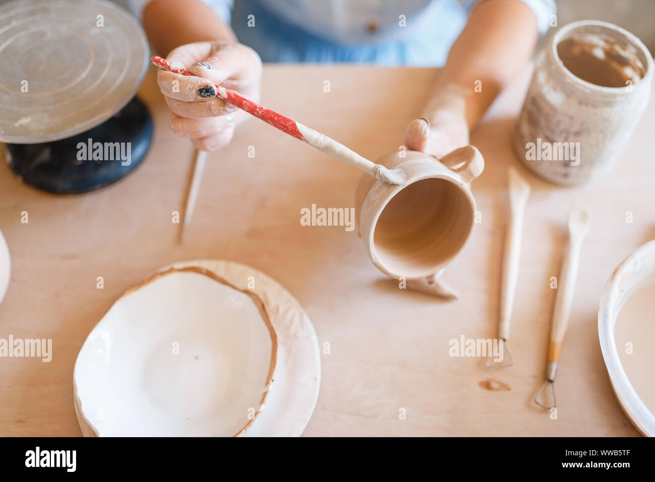 Female potter paints a pot, pottery workshop Stock Photo