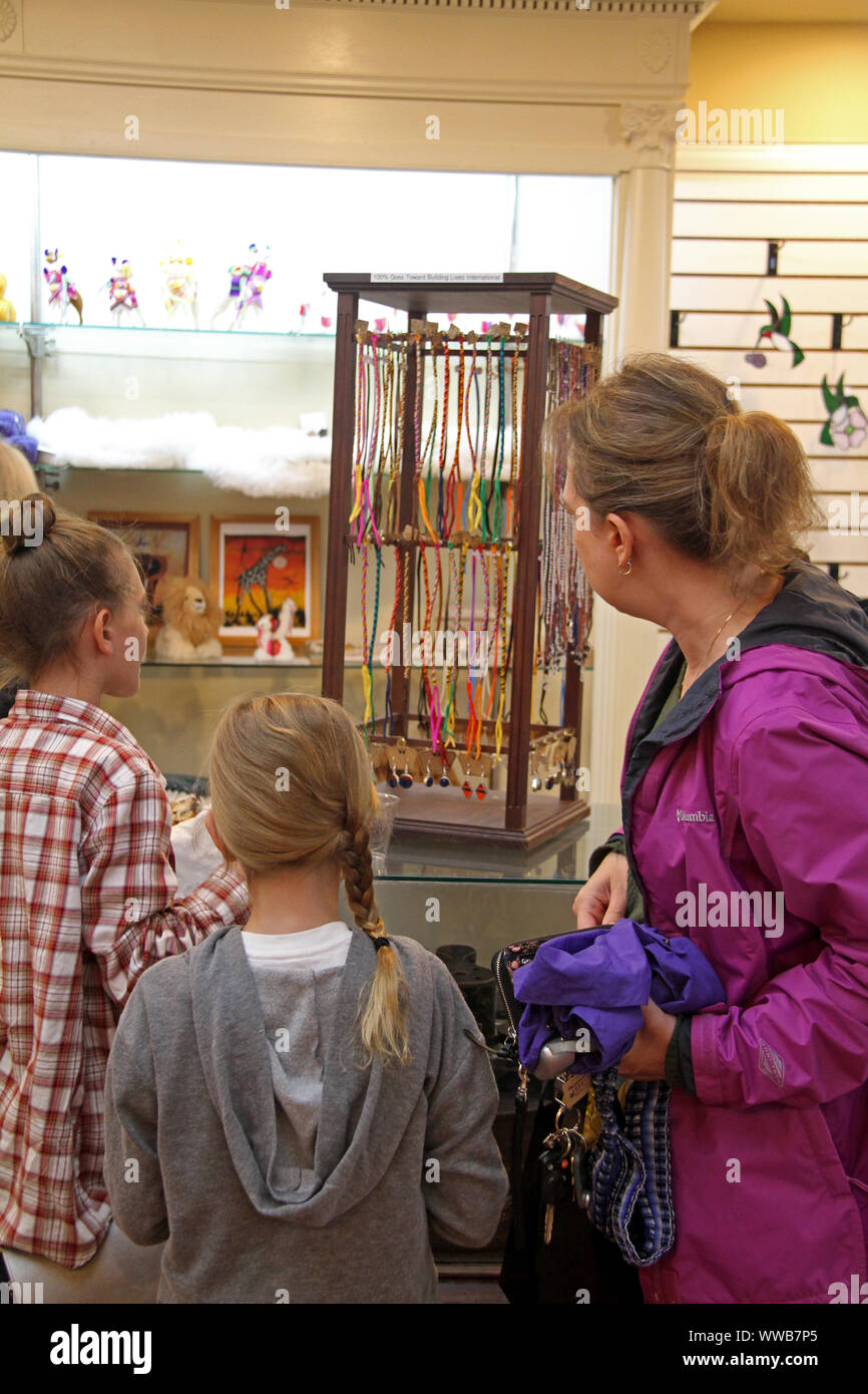 Mother and young daughters shopping for bracelets in gift shop in