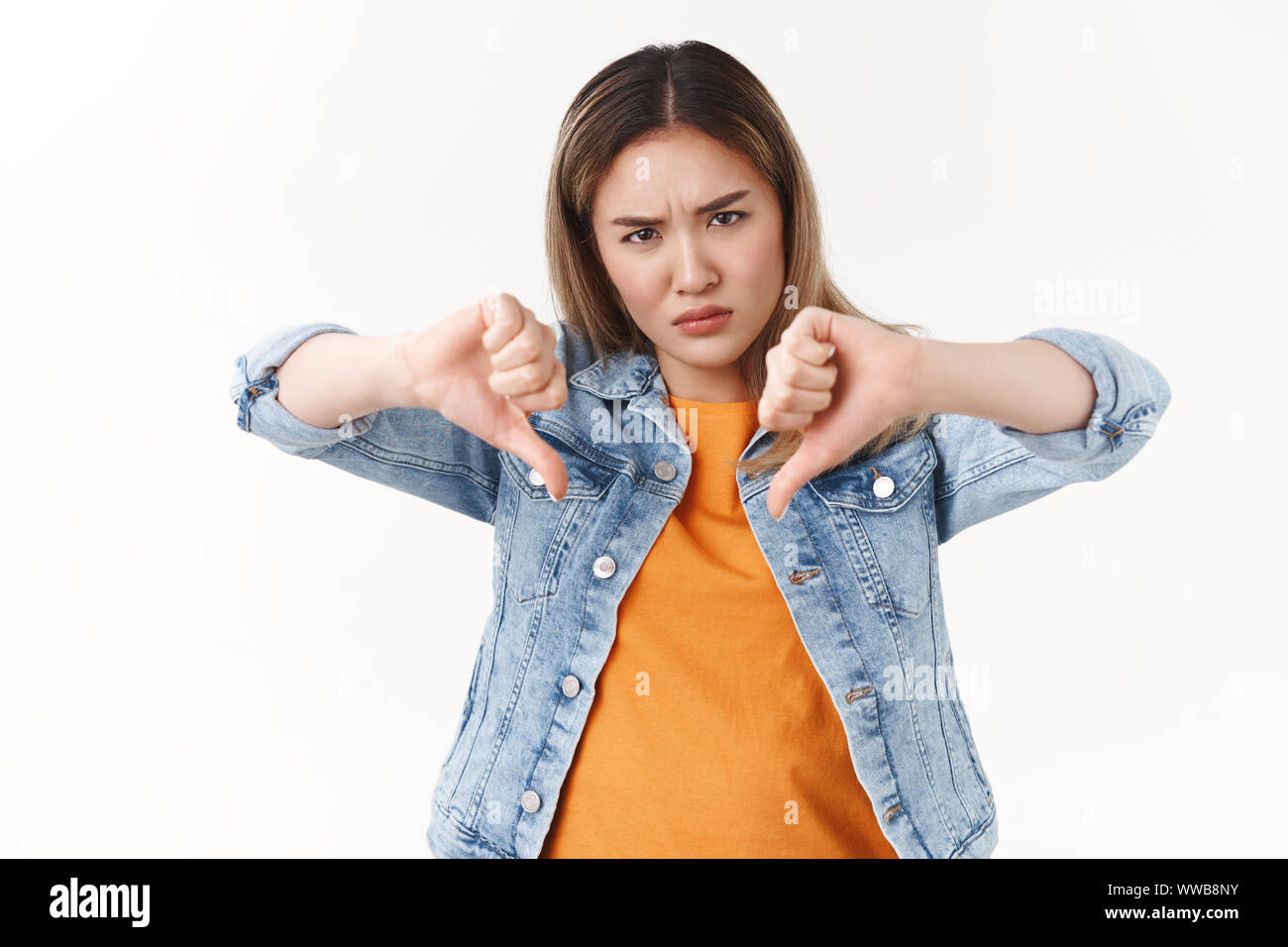 Bad idea wrong choice. Intense displeased angry rebellious asian blond woman express disagree dislike show thumbs down hateful look unwilling see Stock Photo