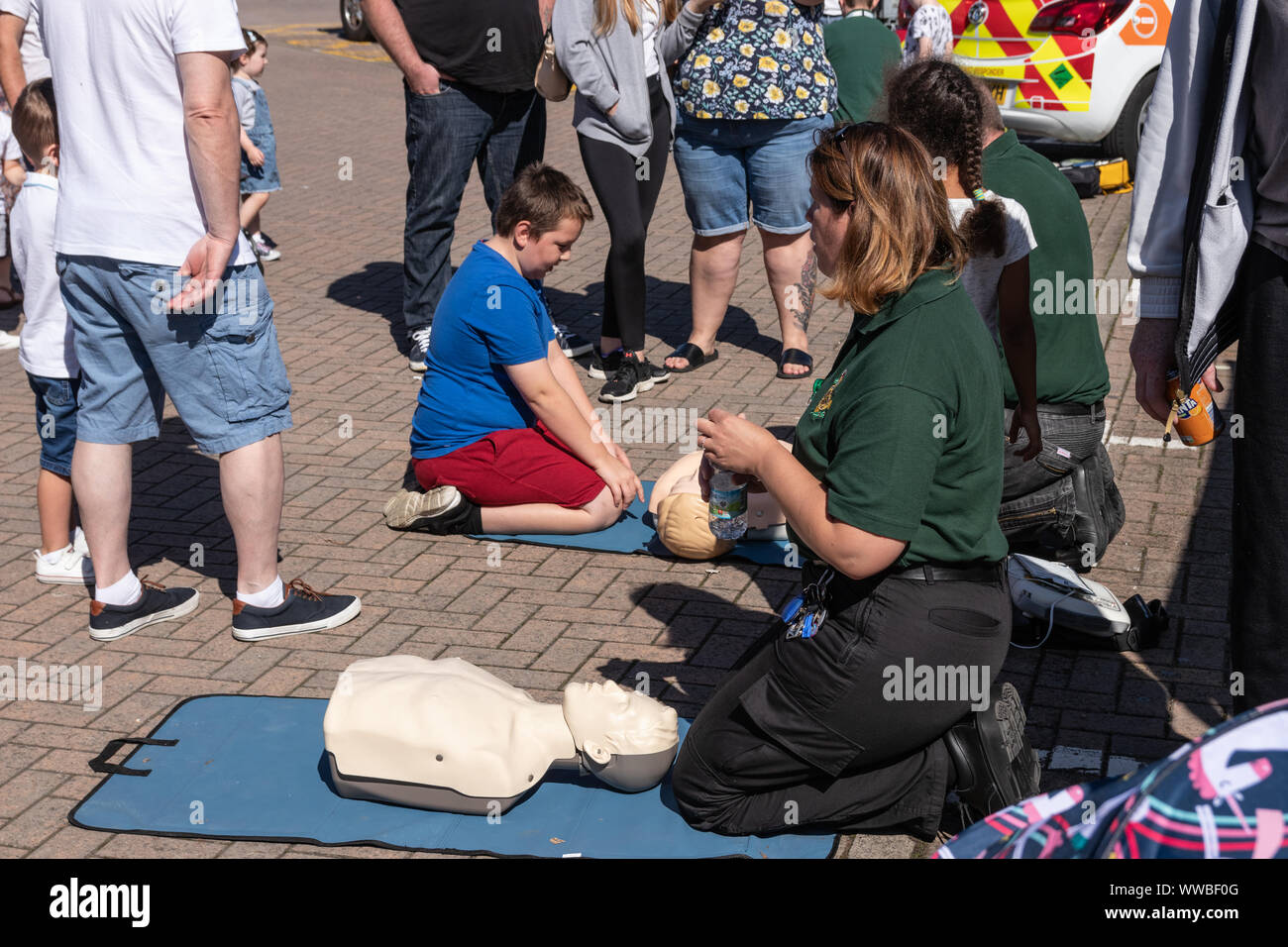 Paramedics teaching resuscitation to people at an open day using a doll or dummy Stock Photo - Alamy