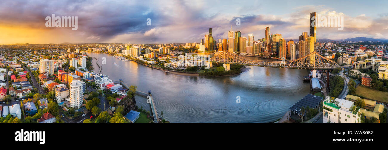 Colourful sunrise with stormy weather over Brisbane city CBD behind Story Bridge across Brisbane river in elevated wide aerial panorama. Stock Photo