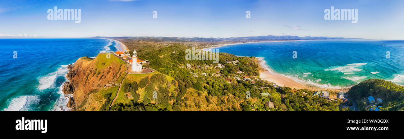 White stone Byron Bay lighthouse on the top of sandstone headland of Australian mainland the most eastern point in aerial panorama towards continent. Stock Photo
