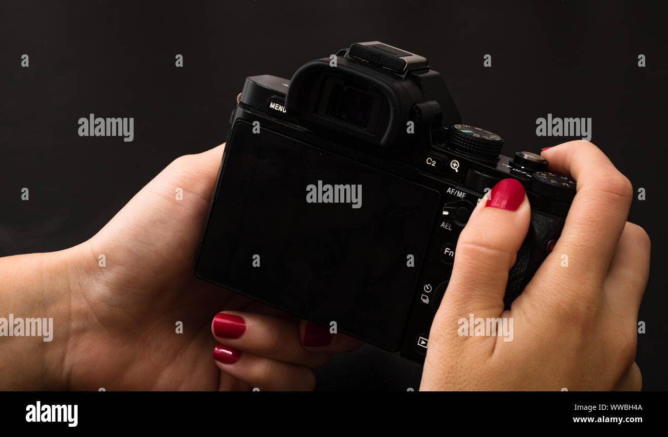 Female hand using photo camera. Close up woman hand on photo camera on black wooden background Stock Photo