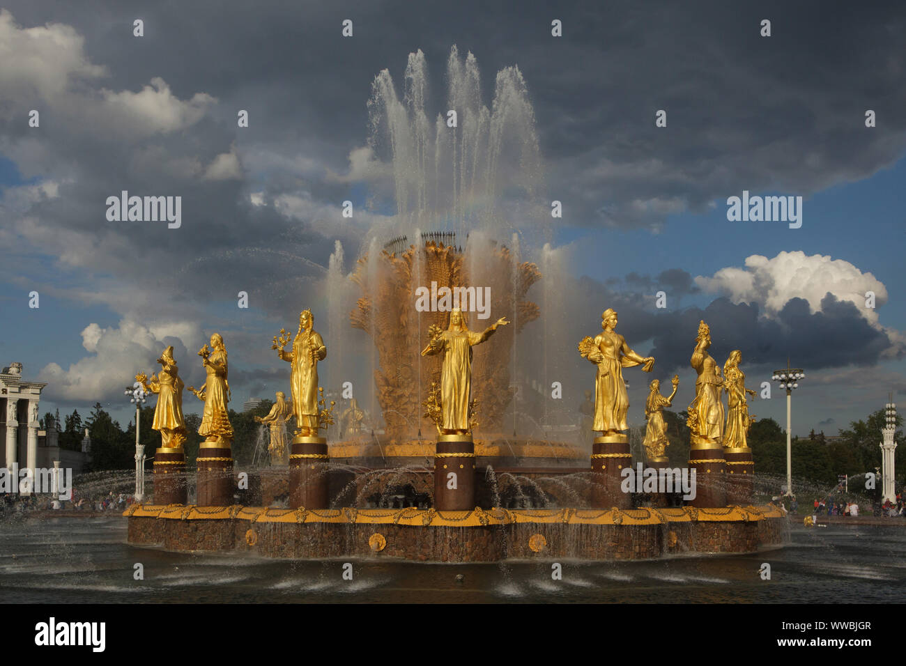 Friendship of Nations (Friendship of Peoples) Fountain on the main square in the VDNH exhibition ground (Exhibition of Achievements of National Economy) in Moscow, Russia. The fountain designed by Soviet architect Konstantin Topuridze decorated with sixteen gilded statues of the nations of the Soviet Union by Soviet sculptors Zinaida Bazehenova, Alexey Teneta, Iosif Chaykov, Zoya Ryleyeva and others was built in 1954. The fountain is also known as the Golden Sheaf. Stock Photo