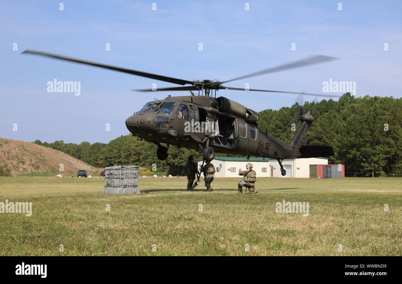 Team from the 75th Ranger Regiment, Fort Benning, Ga., attaches an ammunition package to a Virginia Army National Guard UH-60 Black Hawk for sling load Sept. 11 during the Army Ammunition Transfer Holding Point Team of the Year competition at Fort Pickett, Va. Teams prepared munitions for transport by configuring, inspecting, and ensuring the safety and compatibility of loads. ATHP started Sept. 9 and ran through Sept. 13. Teams of five Soldiers, from 75th Ranger Regiment, 10th Mountain Division, and 1st Cavalry Division, were assessed on ATHP operations and associated tasks that facilitate th Stock Photo