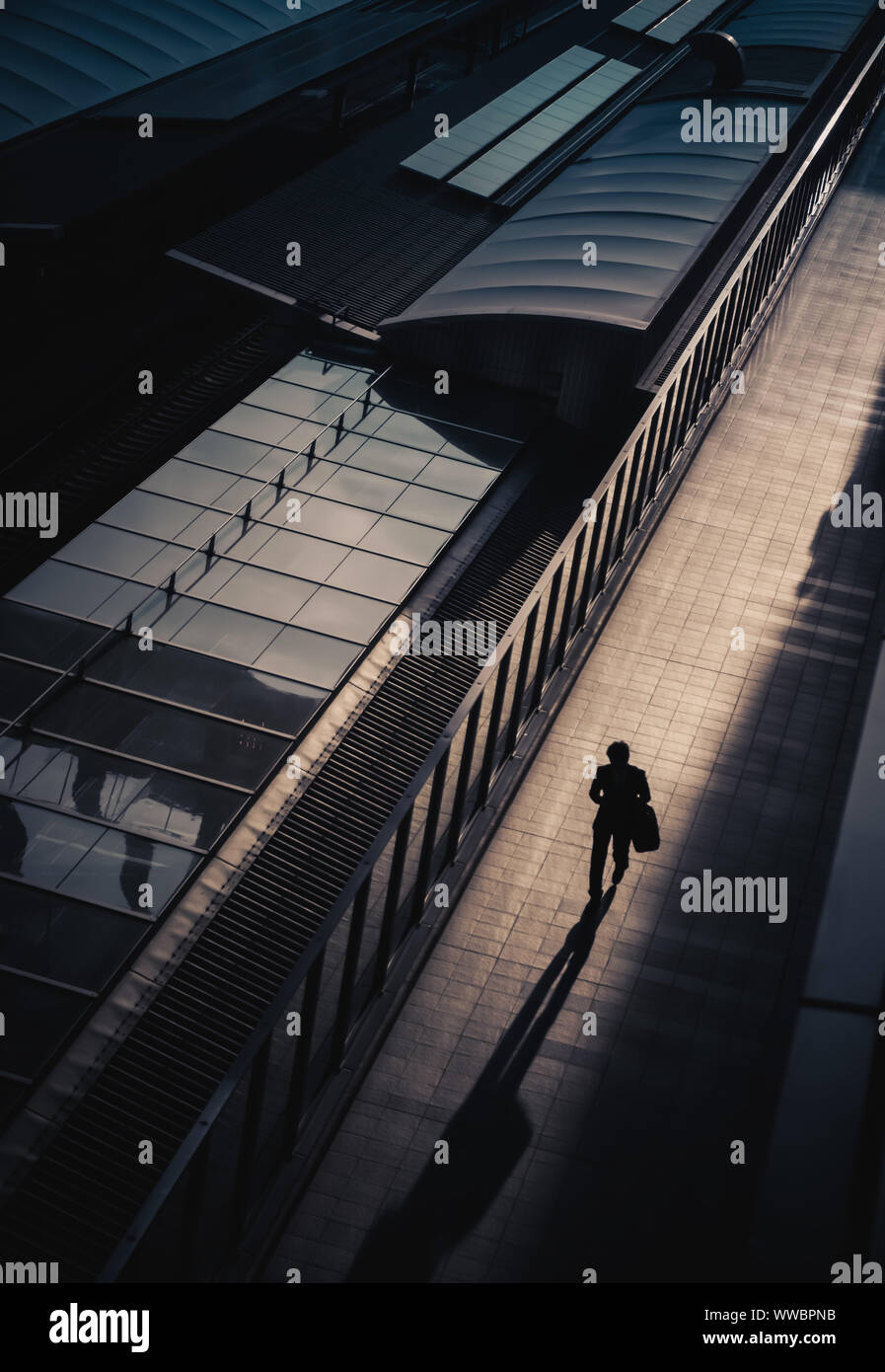 View from above of a person in shadow walking along a sunlit walkway, in Osaka, Japan Stock Photo