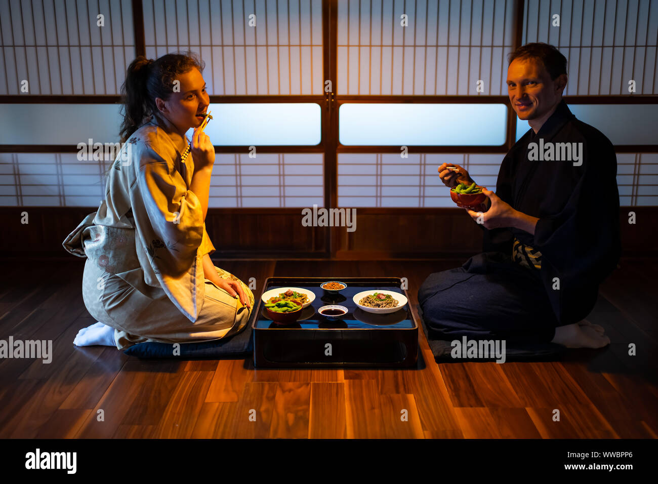 Young couple seiza sitting on floor cushions with Japanese ryokan