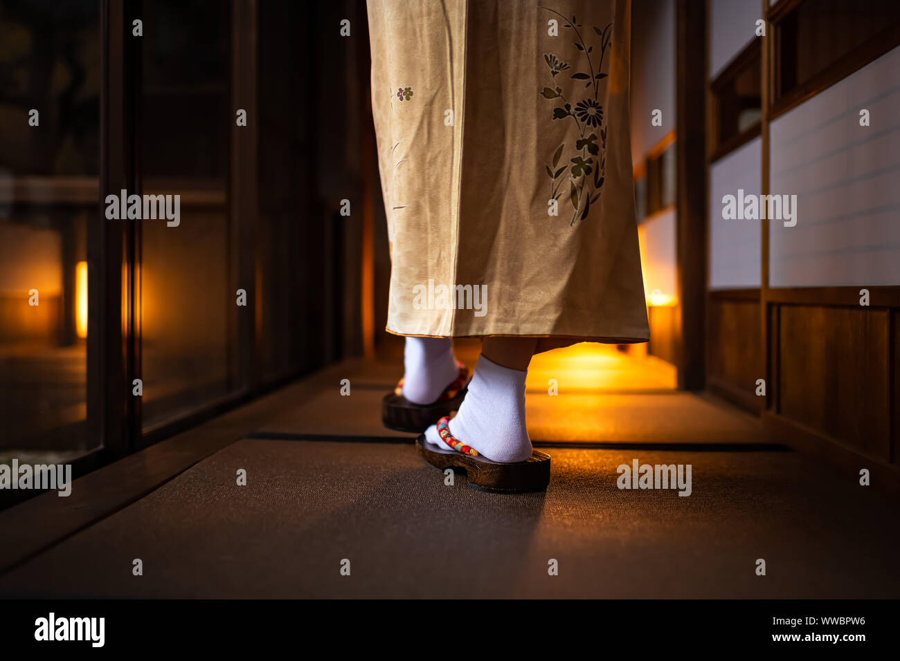 Traditional Japanese home or ryoka with tatami mat floor, shoji sliding paper doors, back of woman feet in kimono and geta shoes tabi socks walking in Stock Photo